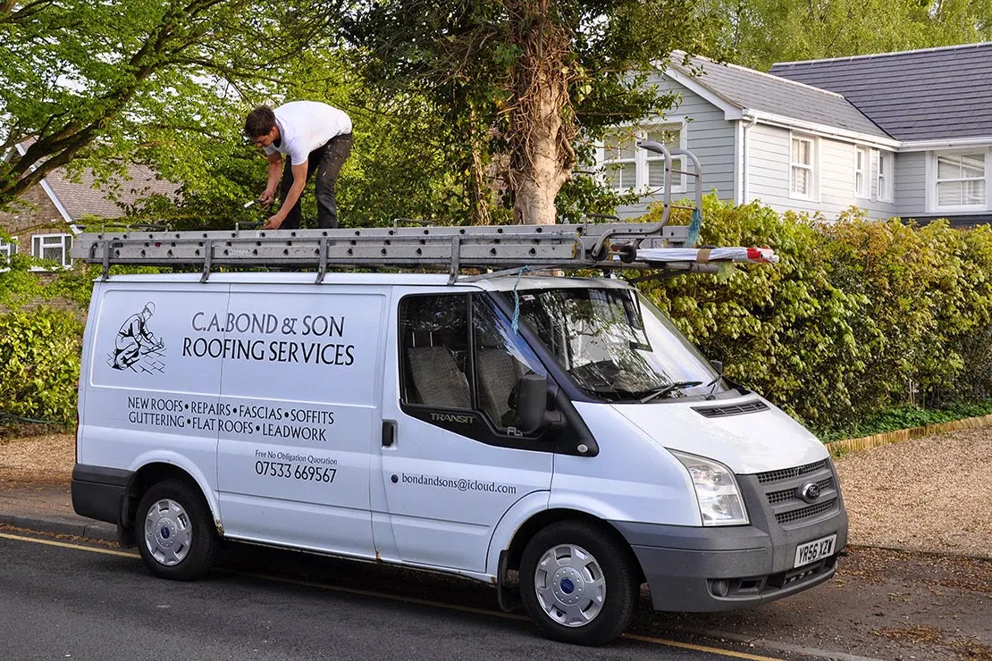 The C.A. Bond & Sons van with a roofer unloading ladders