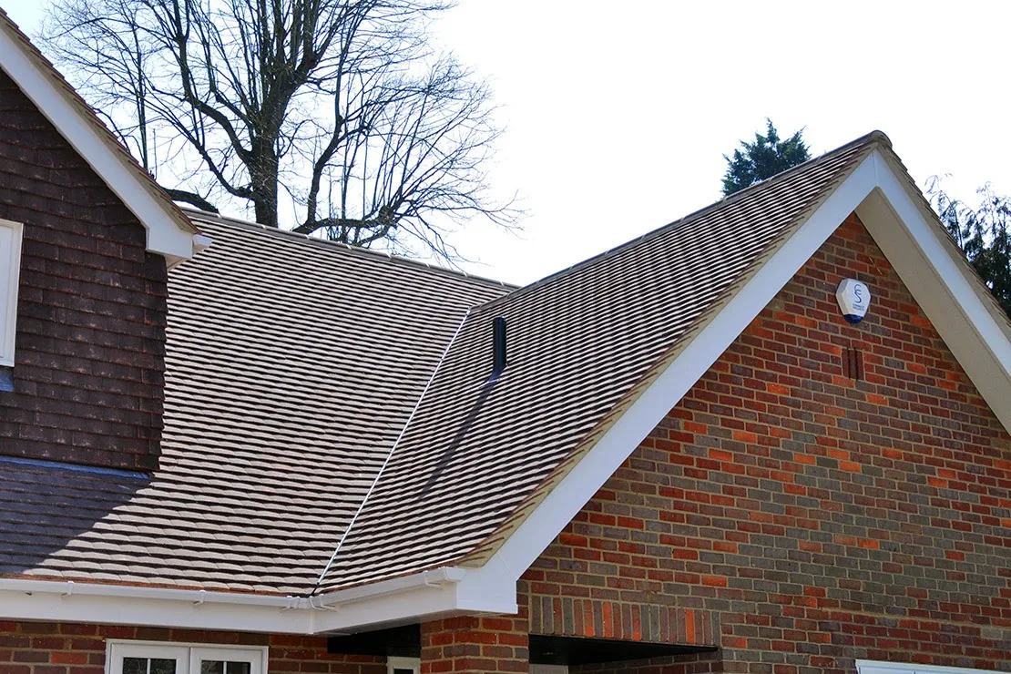 New cross-gabled tiled roof on a brick house with white barge boards